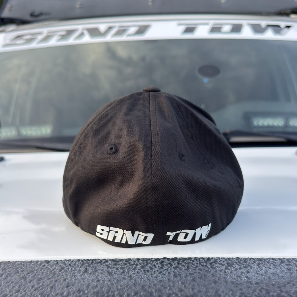 Black cap with 'SAND TOW' branding on a vehicle
