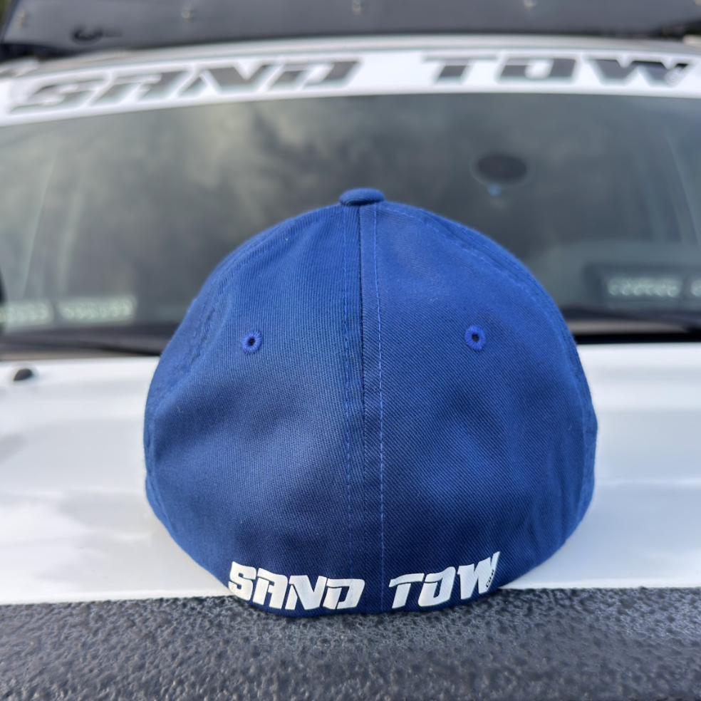 Blue cap with 'Sand Tow' text on a vehicle's open trunk