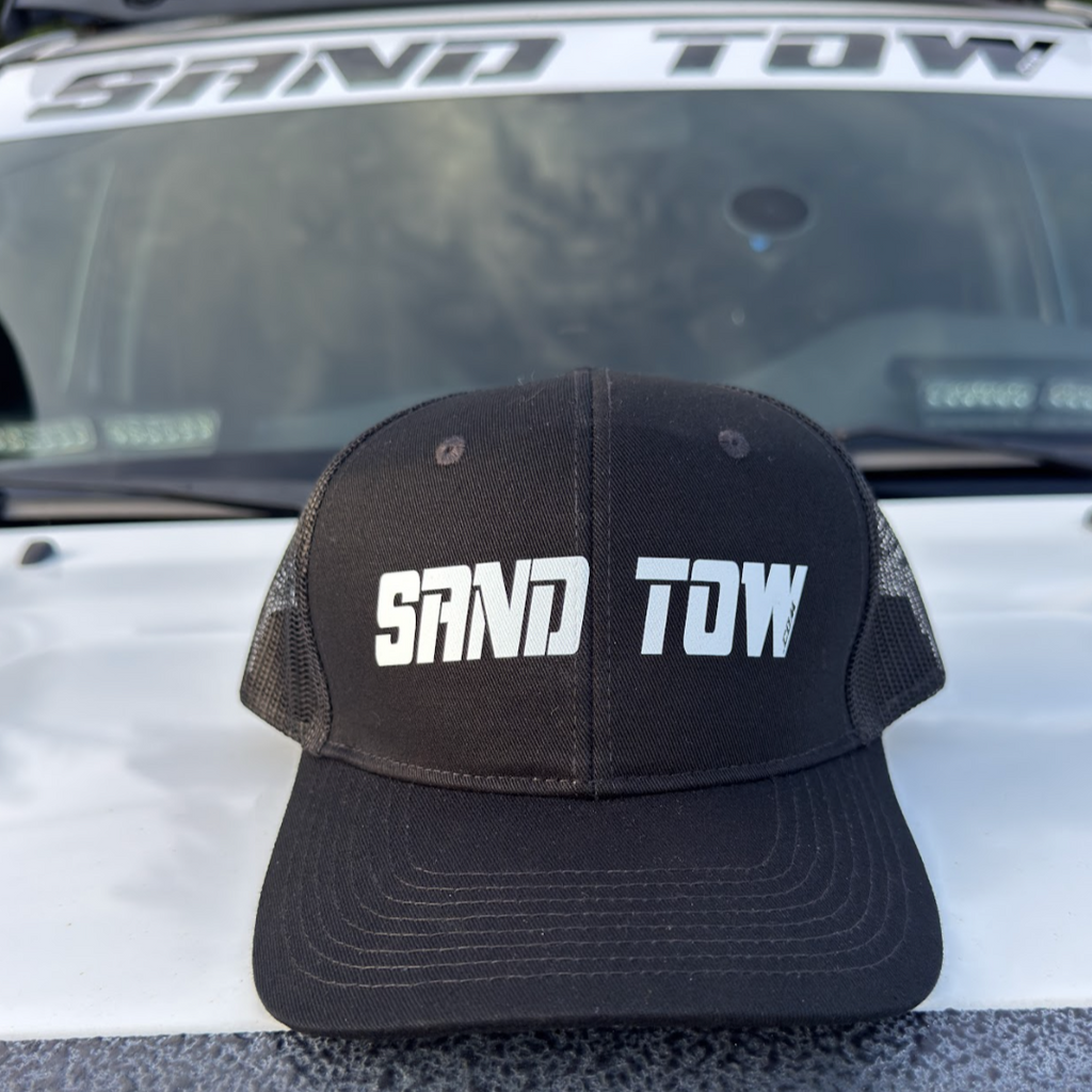 Black cap with 'SAND TOW' text on a vehicle's hood