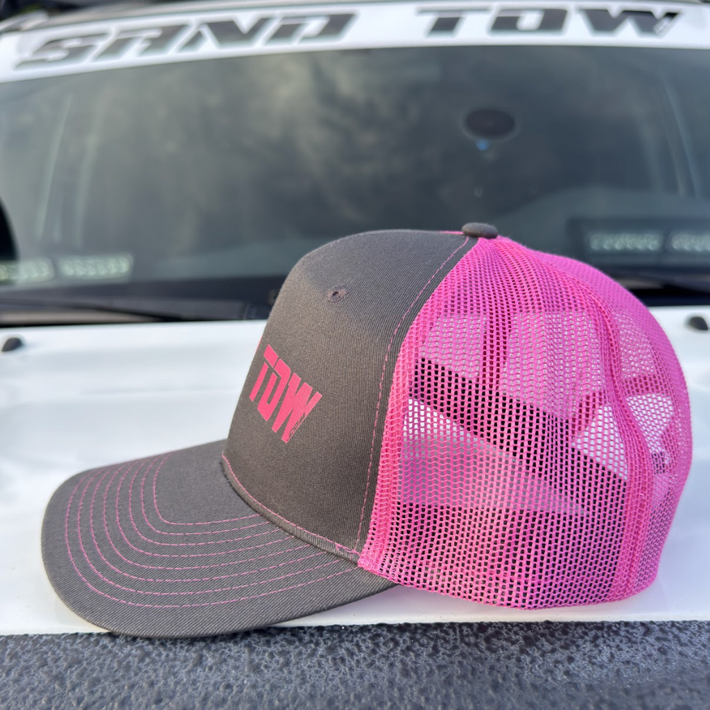 Trucker hat with pink mesh and 'TOW' logo on a vehicle's roof.
