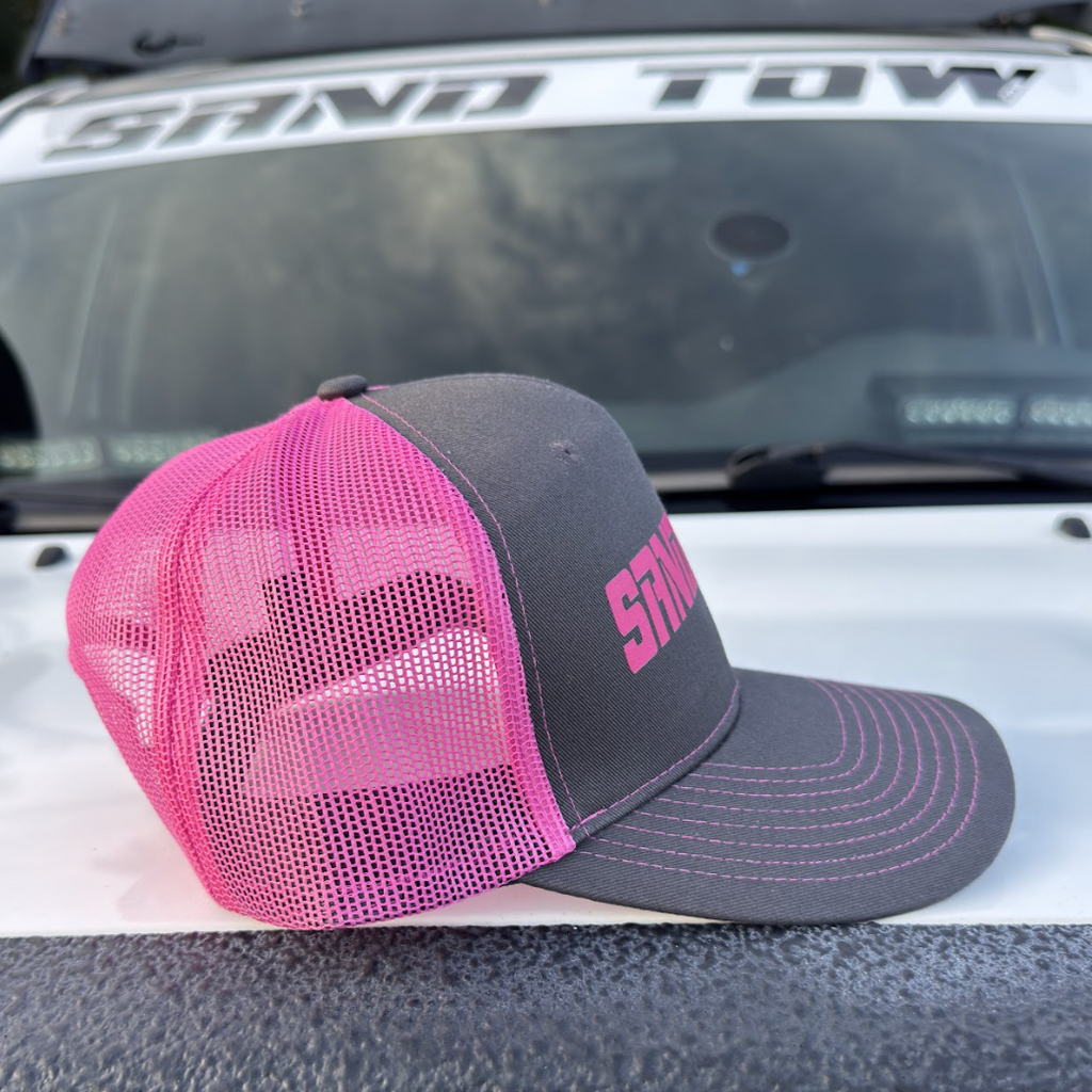 Pink and gray cap with 'SNO' logo on a vehicle's open trunk