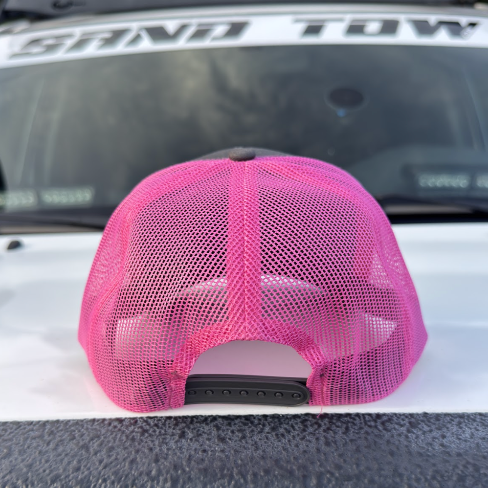Pink mesh cap on a vehicle with 'Sand Tow' written on the windshield.