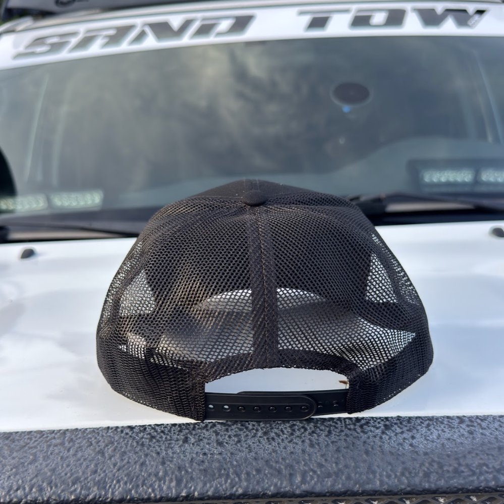 Black mesh cap on a vehicle with 'Sno Tow' written on the windshield.