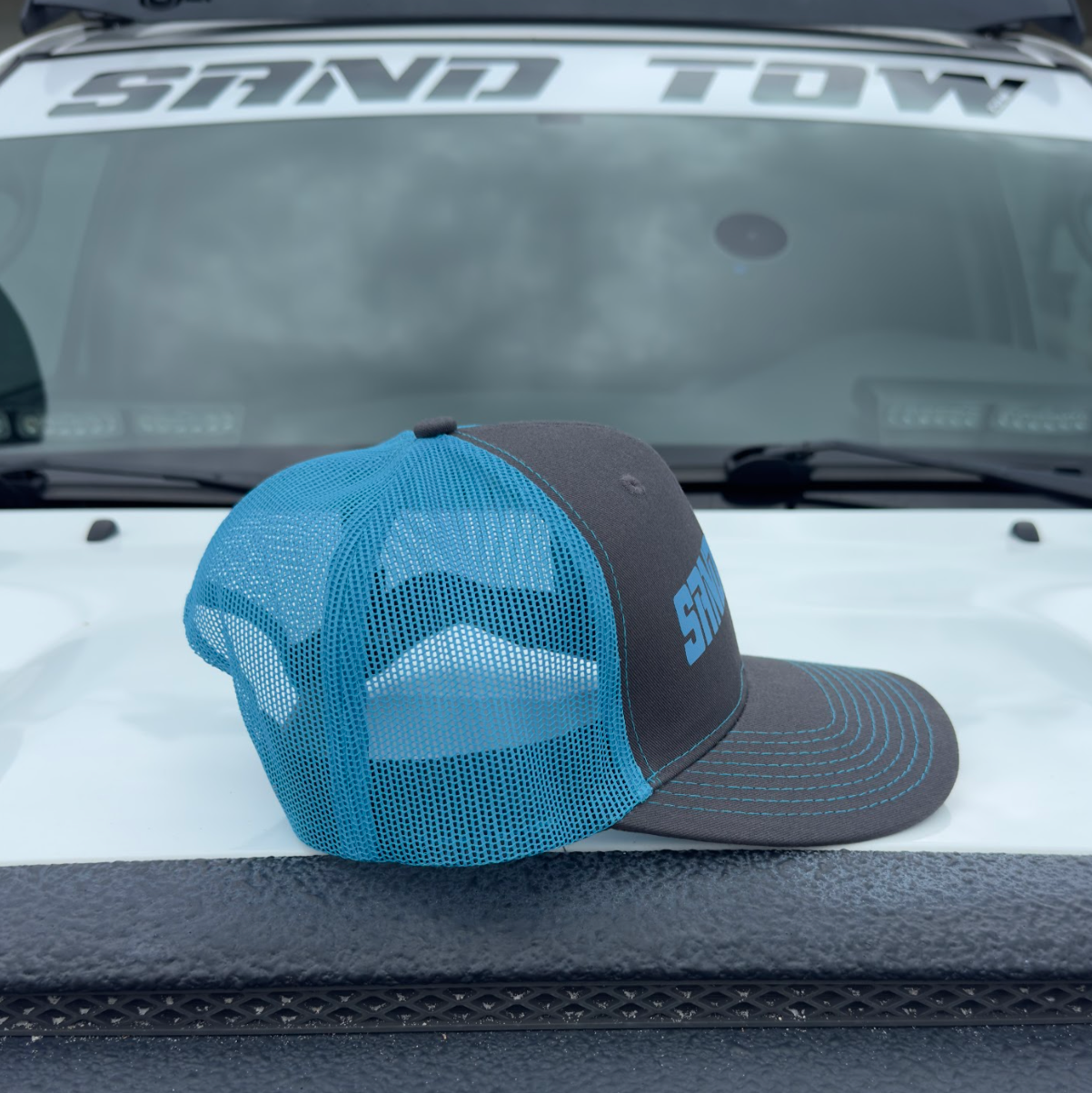 Blue and black cap on a vehicle's open hood with 'SNO TOW' branding.