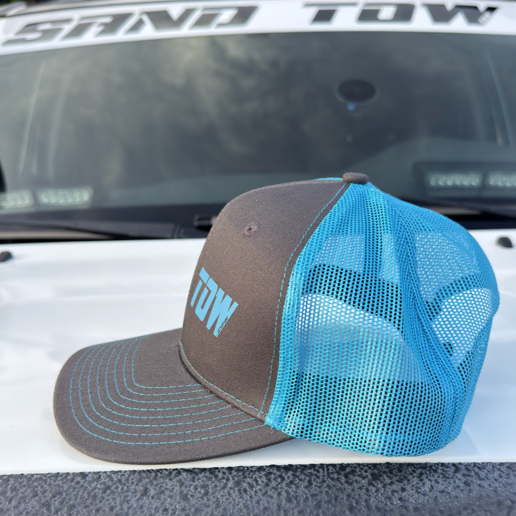 Blue and brown cap with 'TOW' text on a vehicle's open trunk